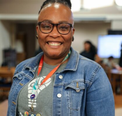 Program staff member smiling at community youth program in classroom setting
