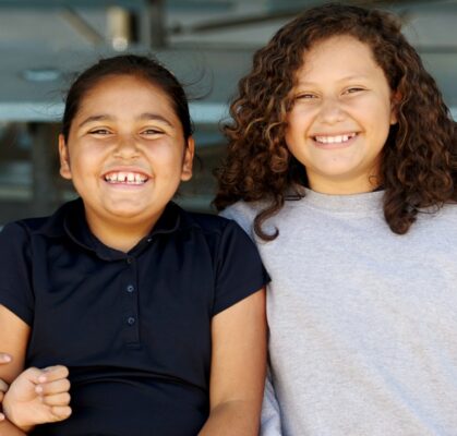 Two young girls smiling together during youth community program activity