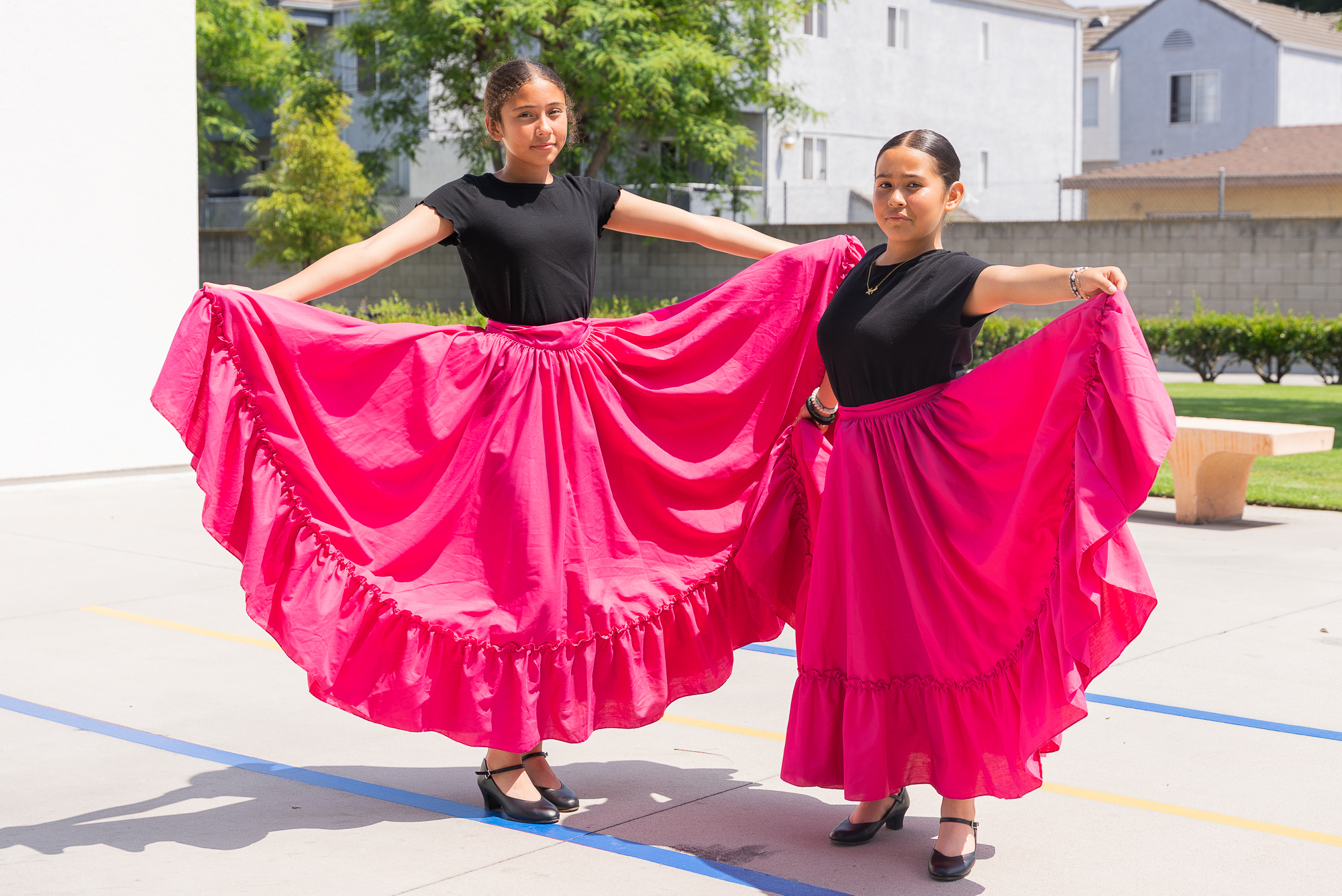 Two Think Together students performing Ballet Folklorico in bright pink dresses outdoors.