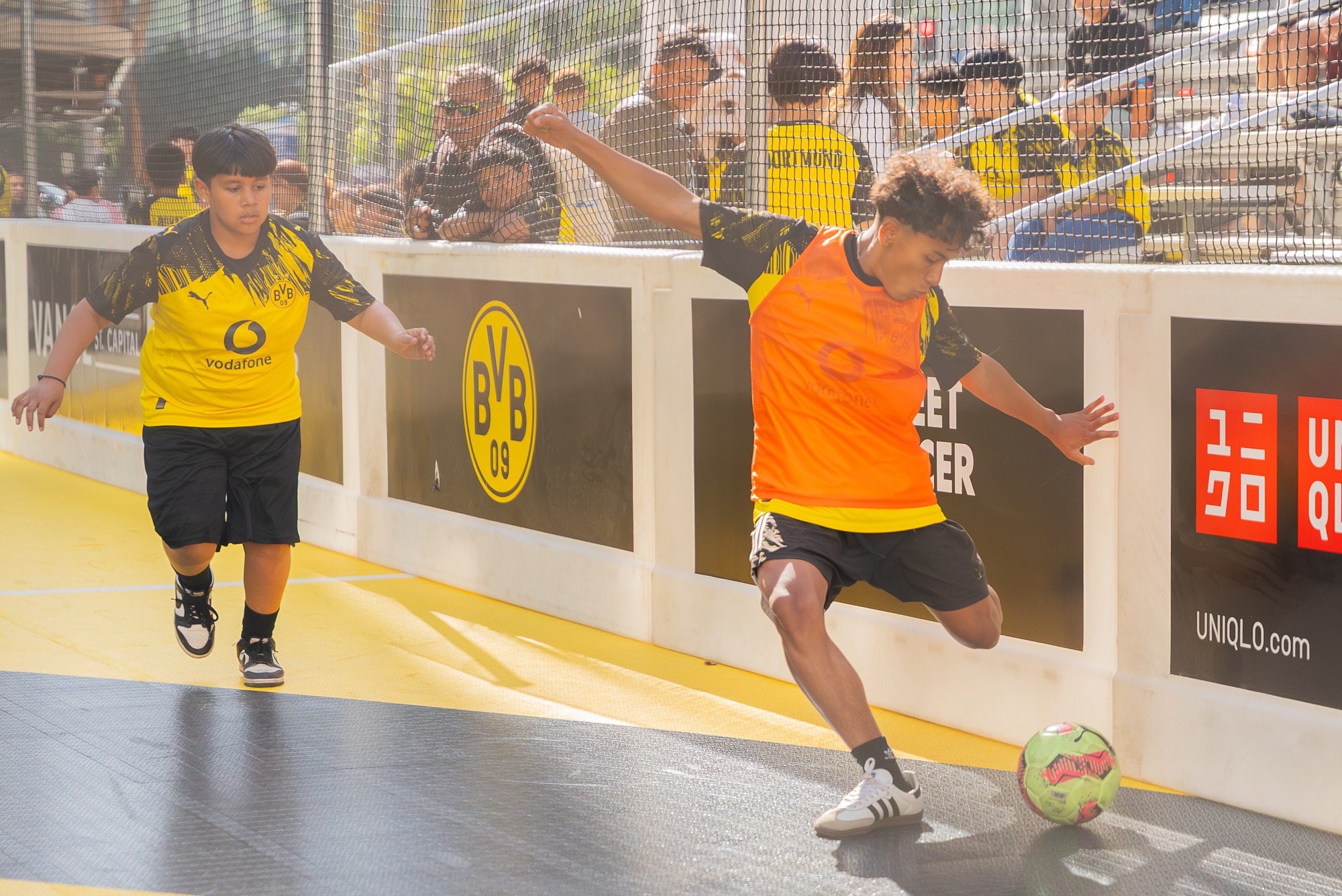 Two youth soccer players competing for the ball during a street soccer tournament game.